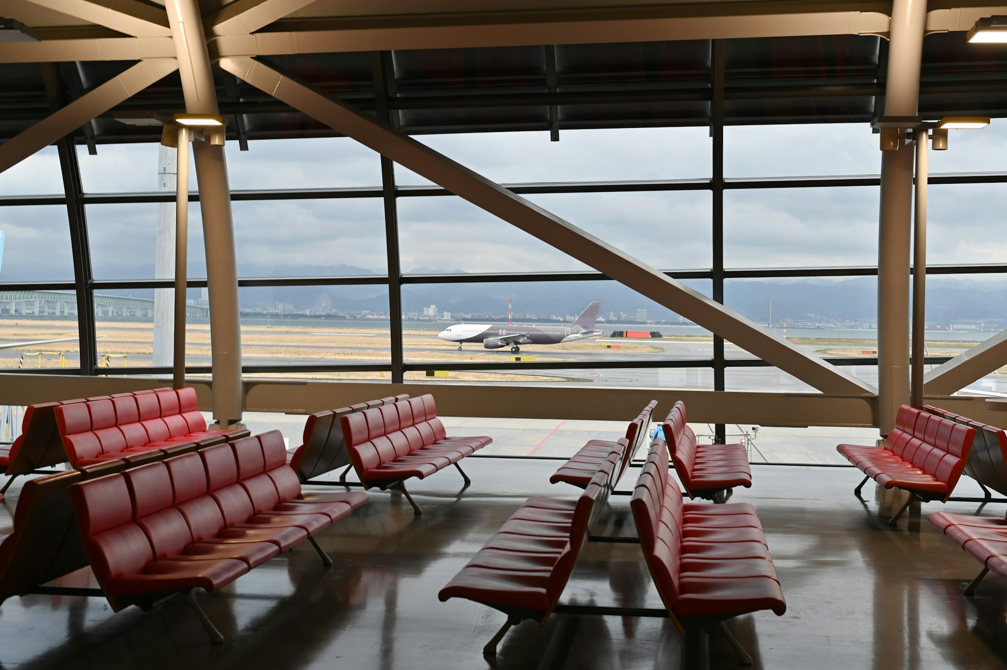 Airport passenger seat and airplane, view from airport terminal.